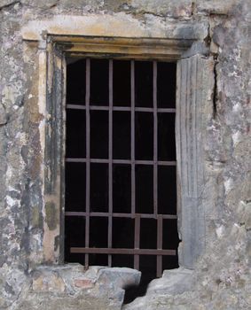 A window with a rusty metal grille of a historic ruined building .Background or texture