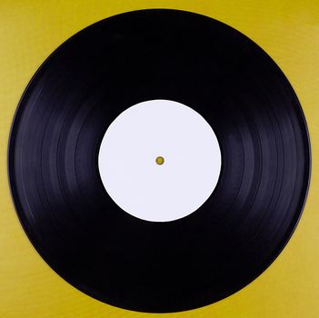 A vinyl record with an empty label isolated on a mustard-colored background.Texture or font