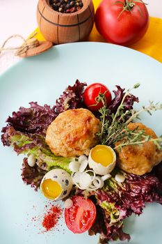On a white plate quail eggs with fried cutlets and decorated with greens