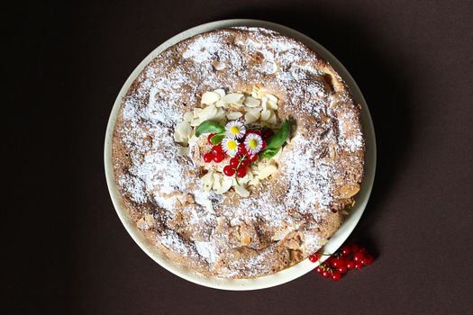 On a plate Apple pie decorated with nuts and red currants.Texture or background