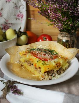 Casserole with minced meat under a cheese crust and a slice of tomato with herbs.Texture or background