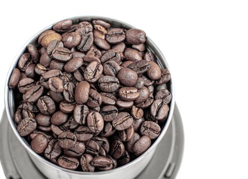 A lot of coffee beans in a metal coffee grinder on a white background. The view from the top. Isolated