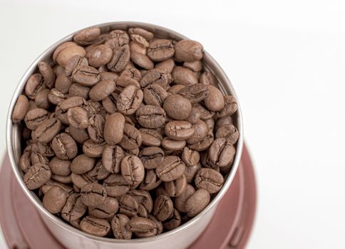 A lot of coffee beans in a metal coffee grinder on a white background. Isolated coffee items