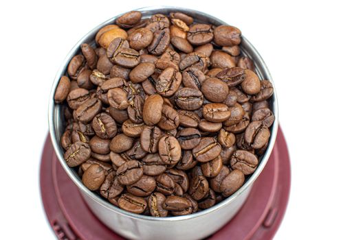 A lot of coffee beans in a metal coffee grinder on a white background. The view from the top. Isolated