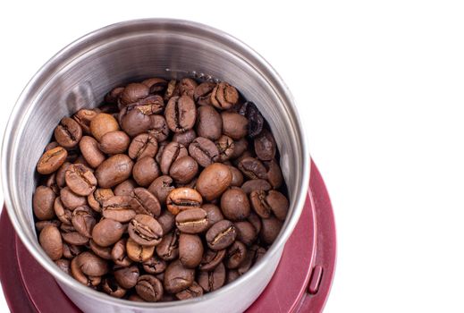 A lot of coffee beans in a metal coffee grinder on a white background. Isolated