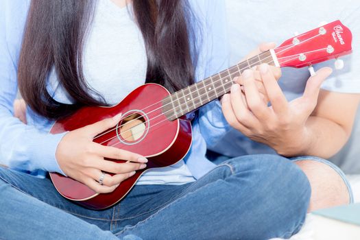 Young Asian couple playing ukulele relaxing with happiness and joyful in bedroom.