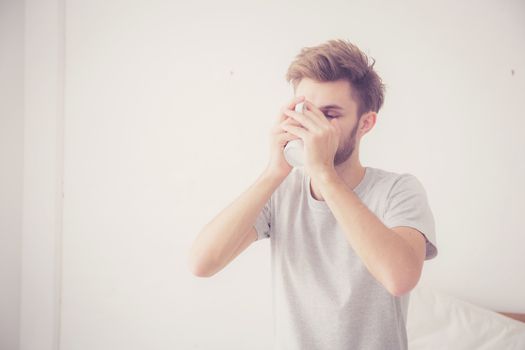 american man with cup of coffee in bedroom with morning.