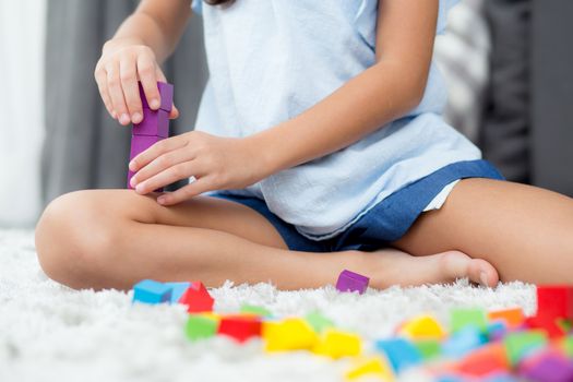 Close up of hand child playing with colorful plastic block at floor. Early learning developing to children with toys.