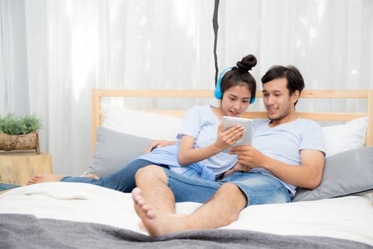 Beautiful asian young couple listening to music with tablet on bed, Love, dating,Young couple in sitting together in bed using a Tablet.