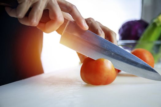 Close up hands women holding knife and cuting fresh Courgette on Cutting Board. Female hand slices raw Japanese Cucumber into circles with knife on cutting Board. healthy food concept..