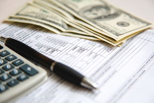 On the calculation sheet are white dollars with a calculator and a pen.Texture.Background.