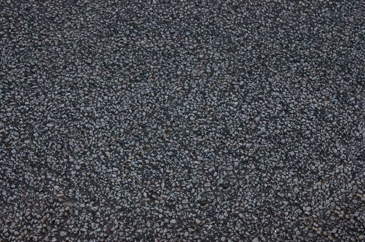 The asphalt road is black with uneven surface.Texture or background.