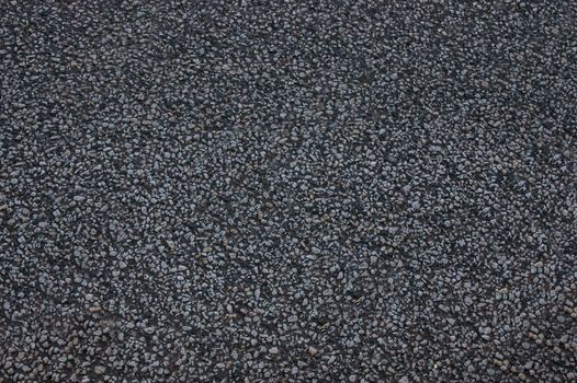The asphalt road is black with uneven surface.Texture or background.