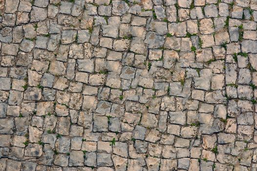 The old curved road of stone sprouted grass .Texture or background.