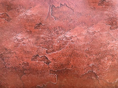 An old cracked wall of red stone with a textured rugged surface
