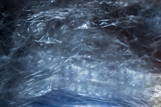 Crumpled transparent film with a blue sheen and textured surface.Texture or background
