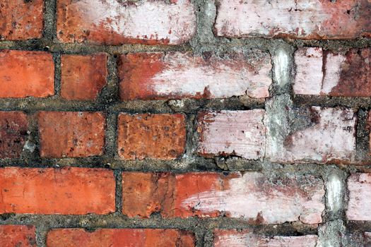 The old wall is made of red brick partially smeared with white paint