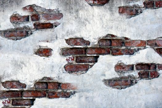 White plaster falls off the cracked red brick wall of the old building.Texture or background