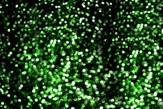 A huge number of unfocused round small balls of green on a black background.Texture or background