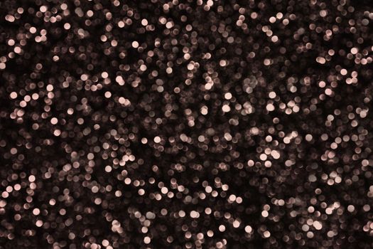 A large number of unfocused round small balls of brown color on a black background.Texture or background
