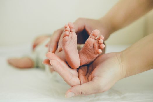 Mom gently takes the baby's little legs