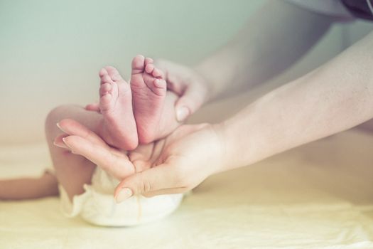 Mom gently massaging the tiny feet of a baby
