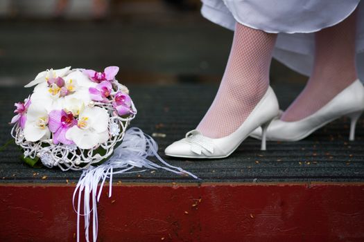 The bride in white wedding shoes stands near a beautiful wedding bouquet