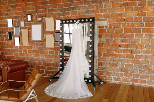 Wedding dress hanging on the mirror in the Studio near the brick wall