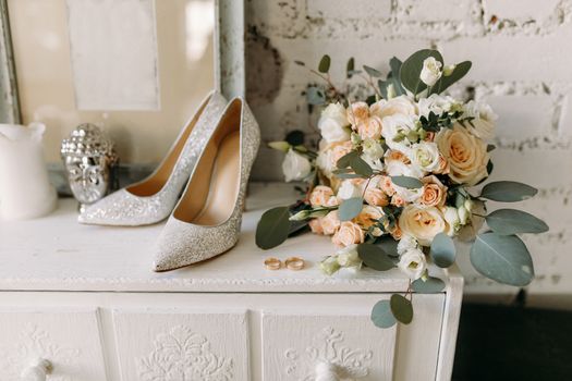 Wedding shoes and wedding paraphernalia, wedding gold rings, wedding bouquet on the table