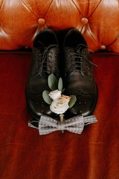 Men's black shoes and wedding accessories on the couch