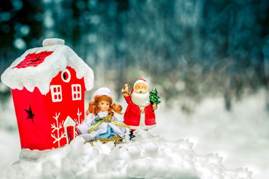 Christmas decorations in the nature of Santa Claus and snow Maiden near the red house