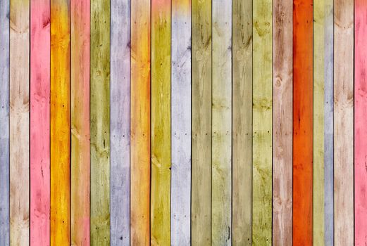 The wooden planks of the old fence are painted in multi-colored paint.Texture or background