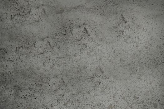 A dirty concrete wall of dark gray color with a textured surface .Texture or background