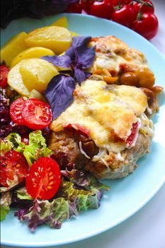 Meat dish with potato slices cherry tomatoes and salad