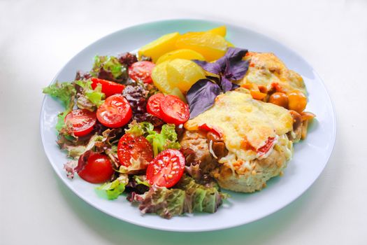 Prepared meat dish with potato slices and cherry tomatoes with salad