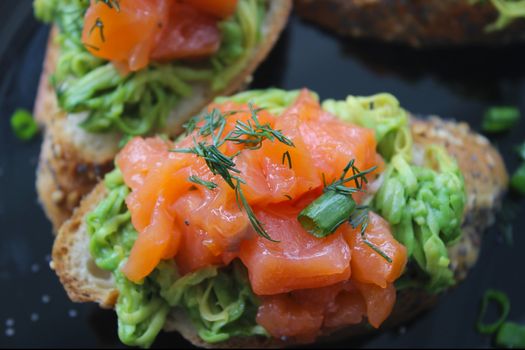 French baguette with pieces of red fish and greens
