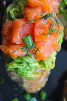 A slice of French bruschetta loaf with red fish and greens