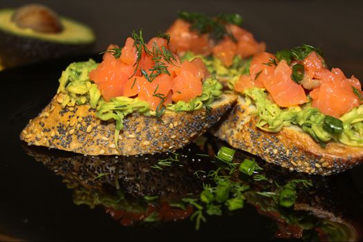 On a plate, sliced French baguette with salmon, herbs and avocado