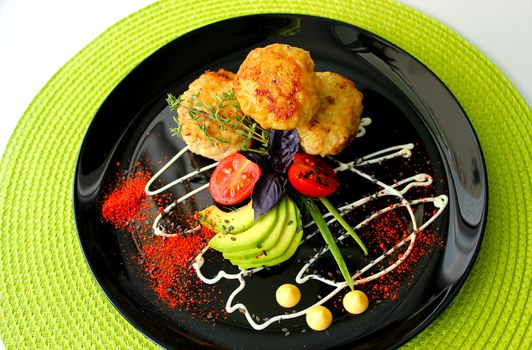 A beautifully designed dish of fried cutlets with cherry tomatoes and zucchini
