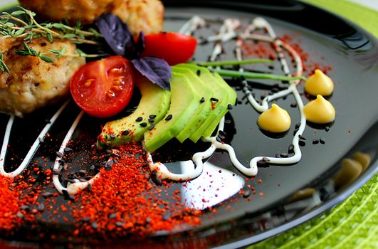 Dish with cutlets decorated with cherry tomatoes and herbs