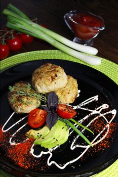 A beautifully designed dish with fried cutlets cherry tomatoes herbs and zucchini slices