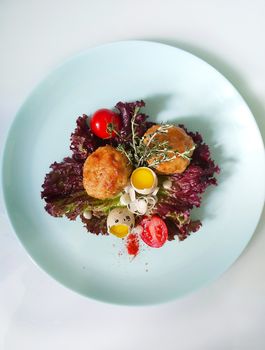 Quail eggs with cutlets on a white serving dish with an isolated white background