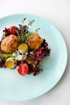 On a plate fried cutlets with quail eggs and tomatoes.Texture or background