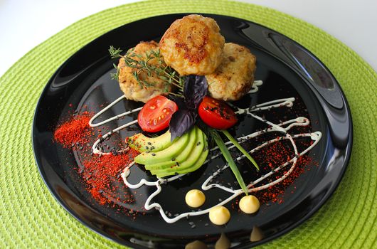 On a plate zucchini with fried cutlets are decorated with mayonnaise and greens with cherry tomatoes