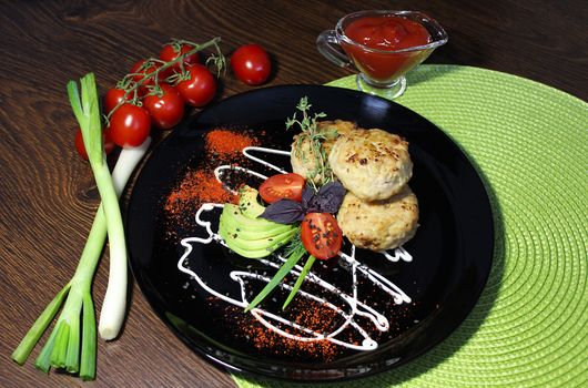 The dish with fried cutlets is decorated with greens and cherry tomatoes