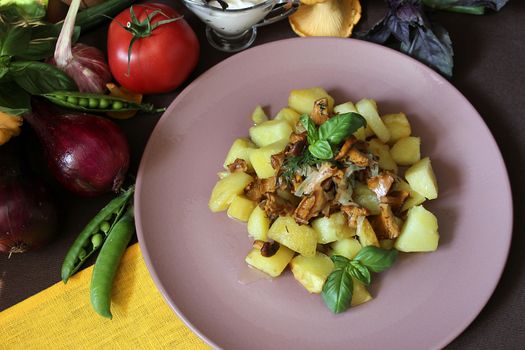 On the table is a plate of fried potatoes and chanterelles with herbs