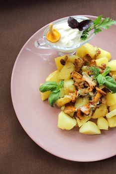 On plates fried potatoes with fried mushrooms and sauce