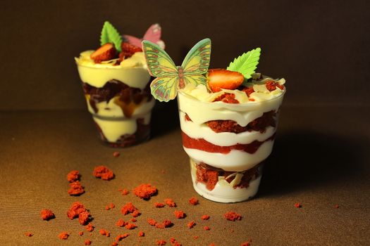In a transparent container ice cream with a cupcake and a slice of strawberry