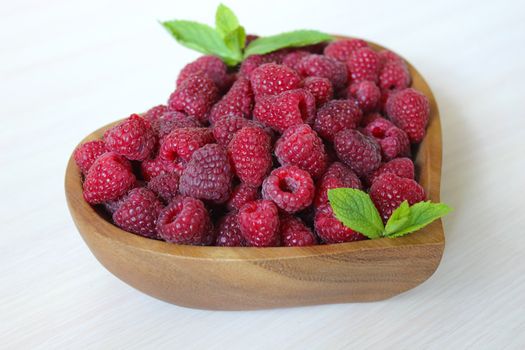 Ripe garden raspberries in a wooden container on the table