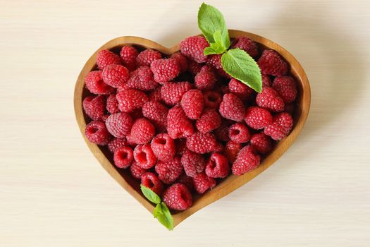 Large crop of raspberries in a wooden container on a white background
